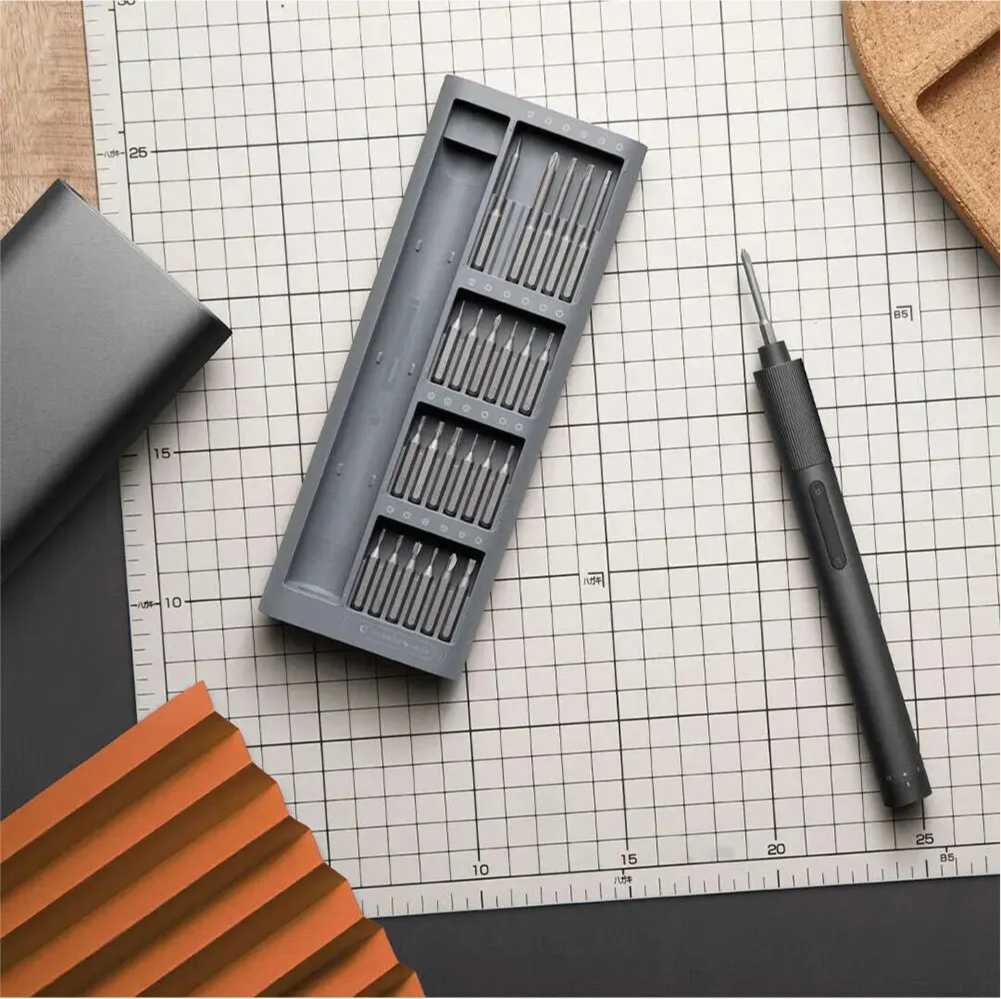 Set of screwdrivers in a gray case on a grid surface with a screwdriver and notebook.